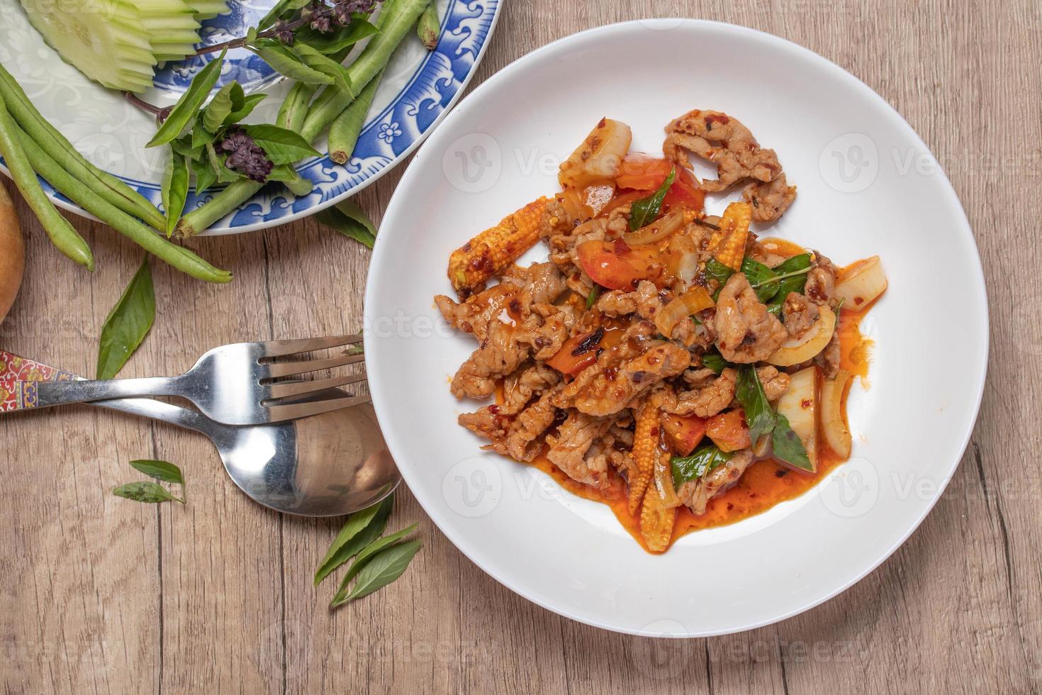 carne de porco frita em pasta de pimentão com tomate e cebola em um prato branco foto