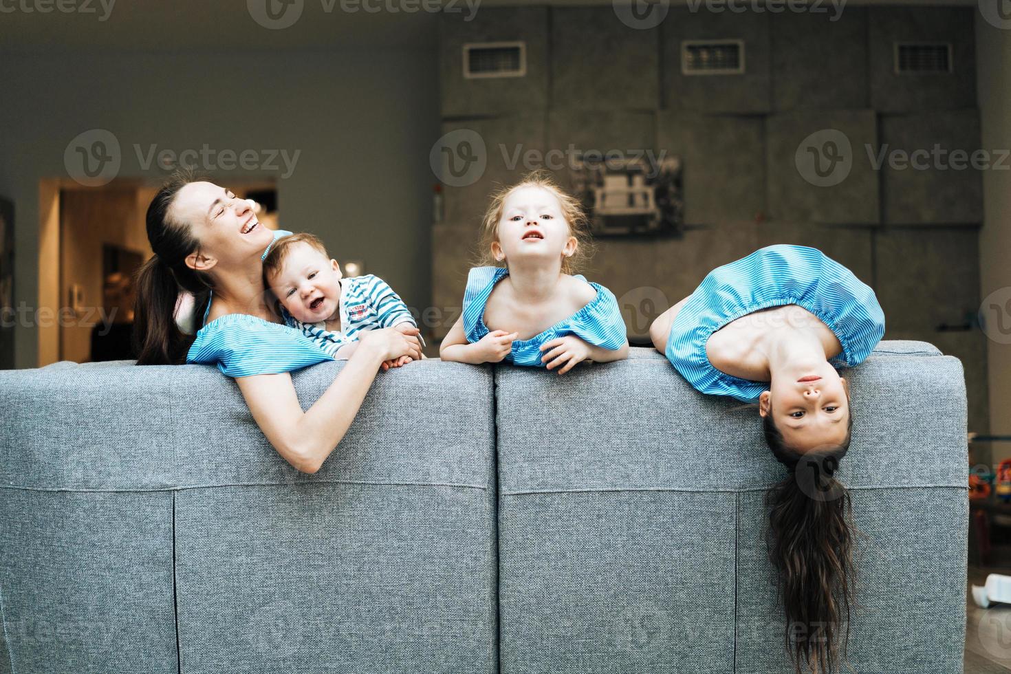 mãe, duas filhas e um filho pequeno no sofá foto