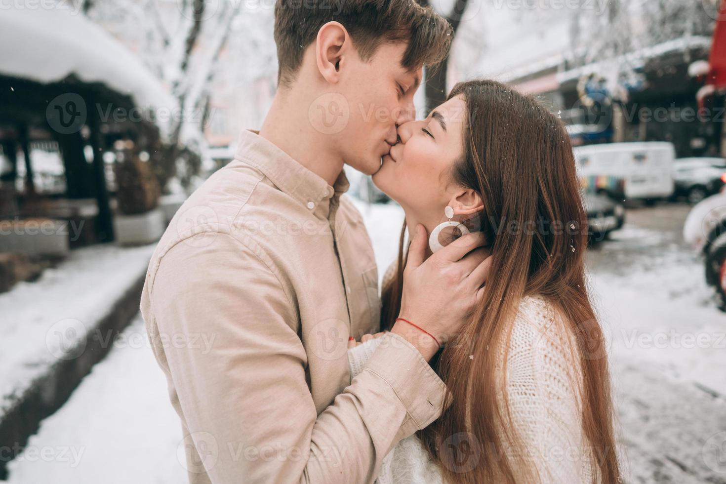rapaz e linda garota se beijam em um parque nevado foto