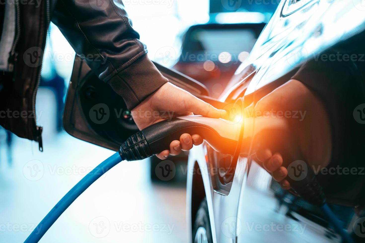 mão humana está segurando o carregamento do carro elétrico conectar ao carro elétrico foto