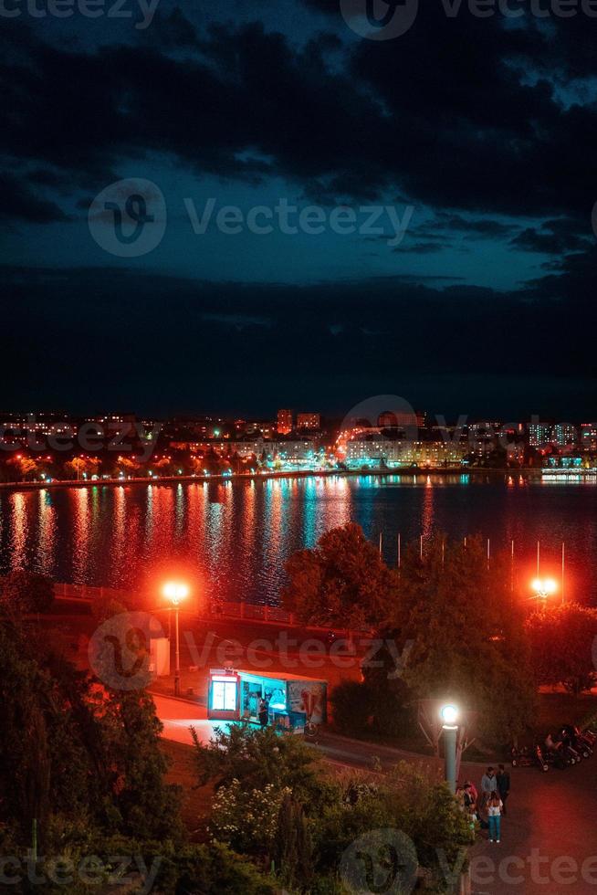 cidade à noite à beira do lago. aterro. foto