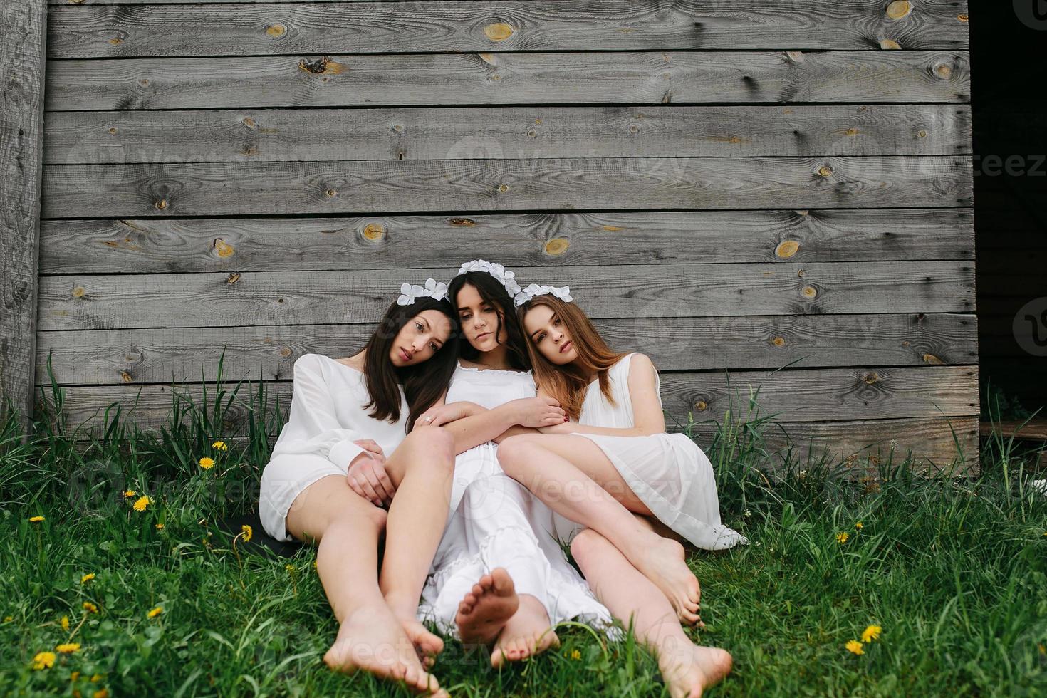 três garotas encantadoras perto de uma casa de madeira foto