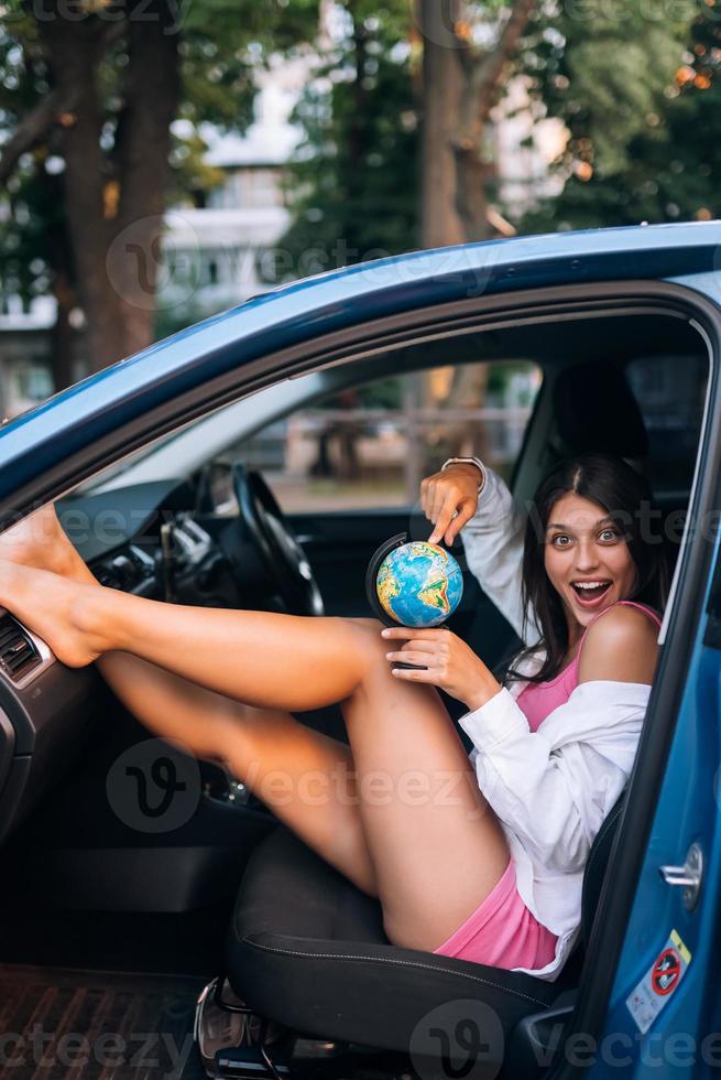 jovem sentada em um carro e segurando um globo foto