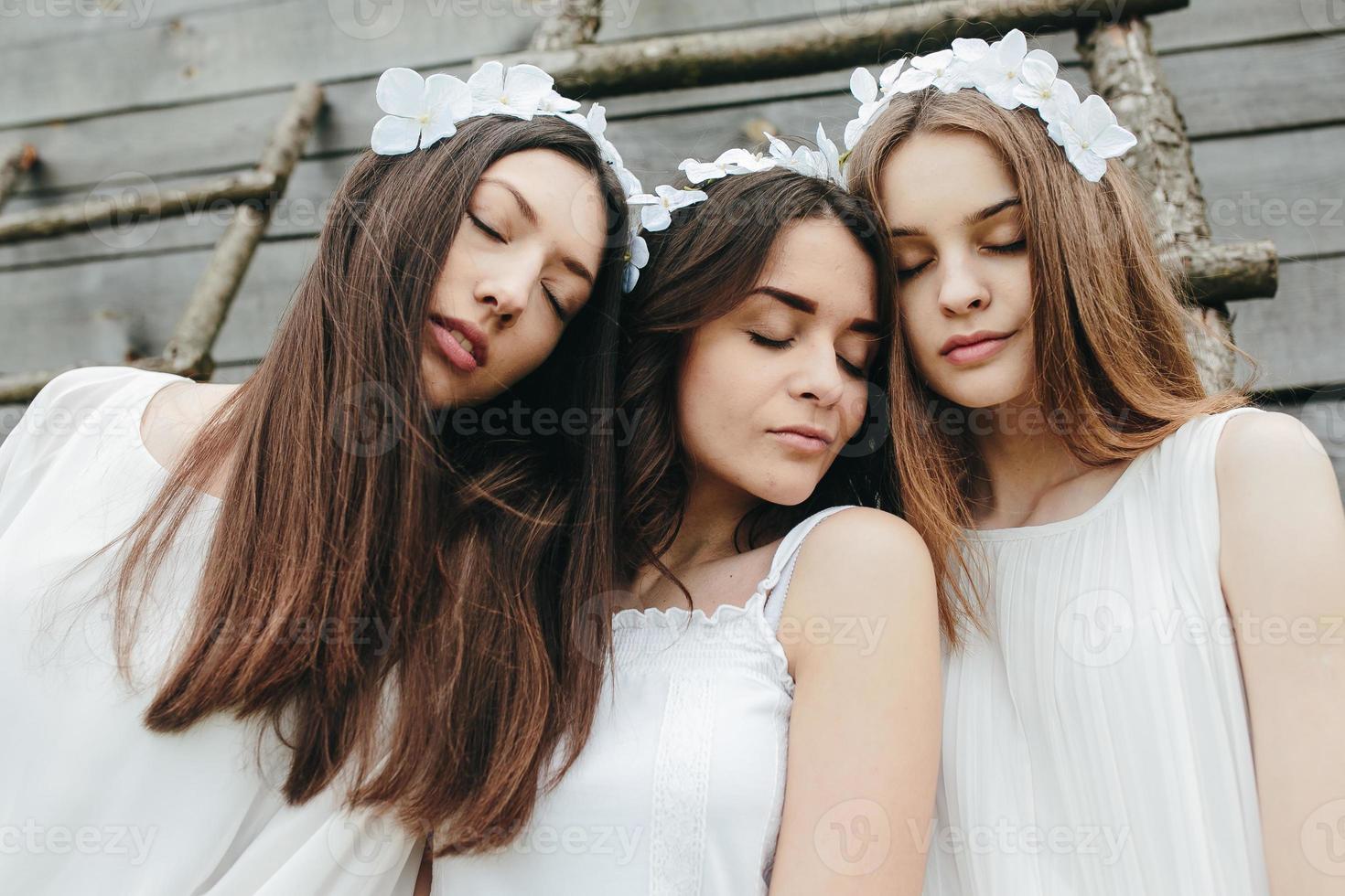 três garotas encantadoras em uma escada perto de uma casa de madeira foto