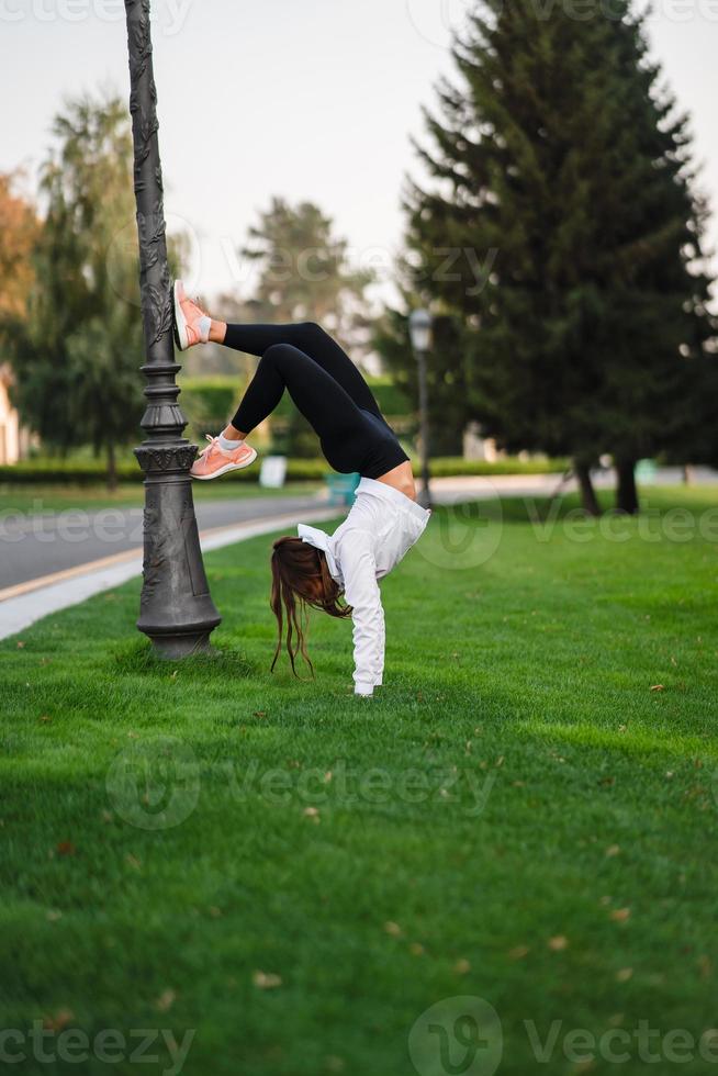 mulher magra atraente fazendo um backbend enquanto mostra uma cambalhota. foto