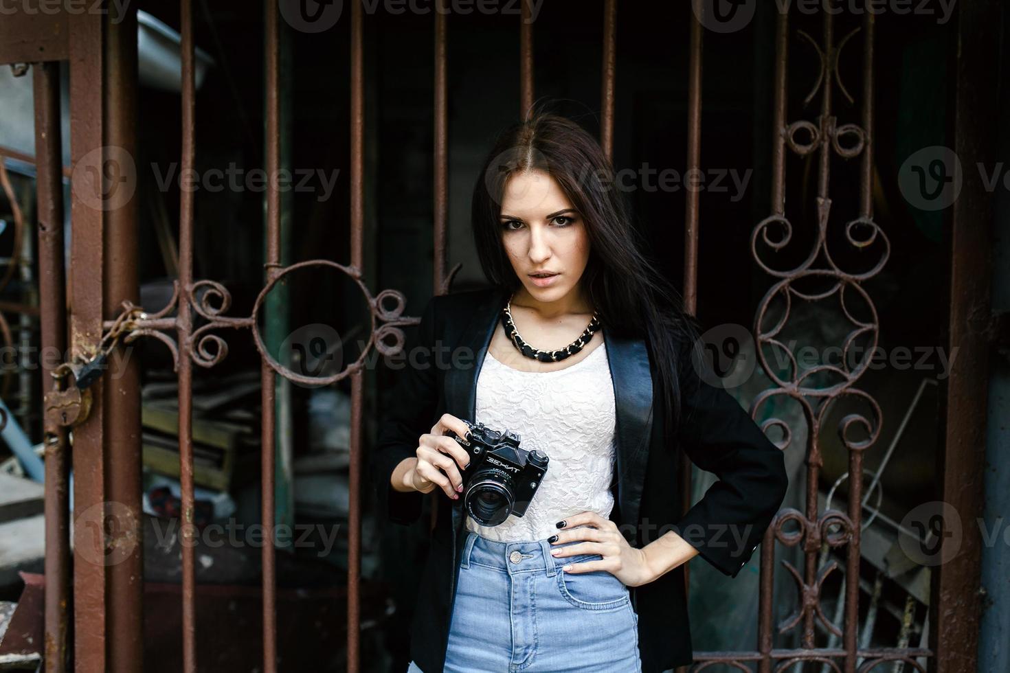 linda garota de pé contra uma parede com uma câmera foto