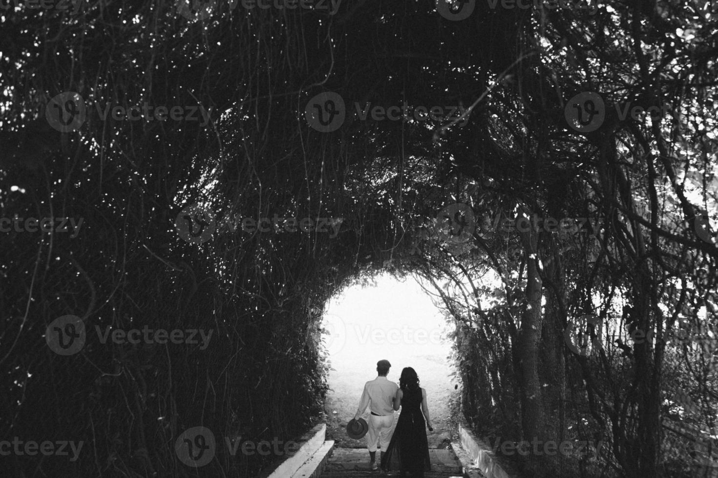 casal andando pelo túnel de árvores foto