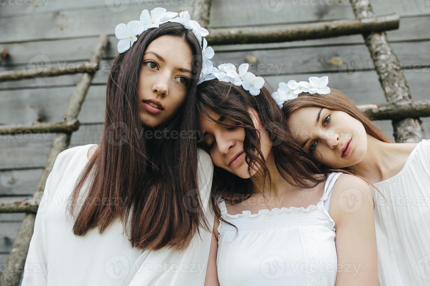 três garotas encantadoras em uma escada perto de uma casa de madeira foto