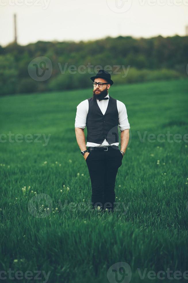 homem com barba e óculos de sol andando no campo foto