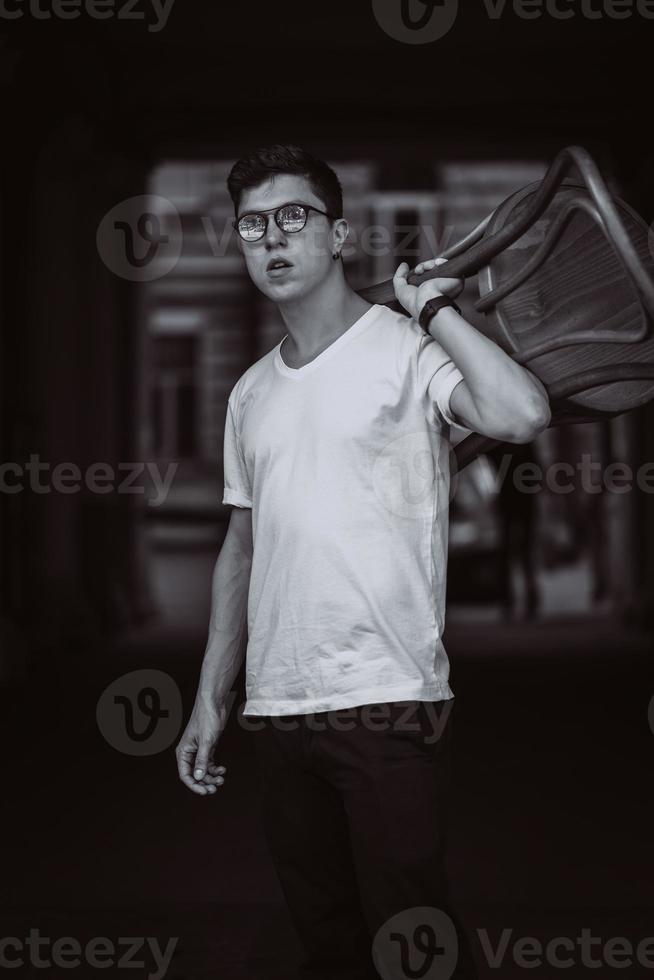 retrato de homens em pé com cadeira de camiseta branca e óculos de sol na rua foto