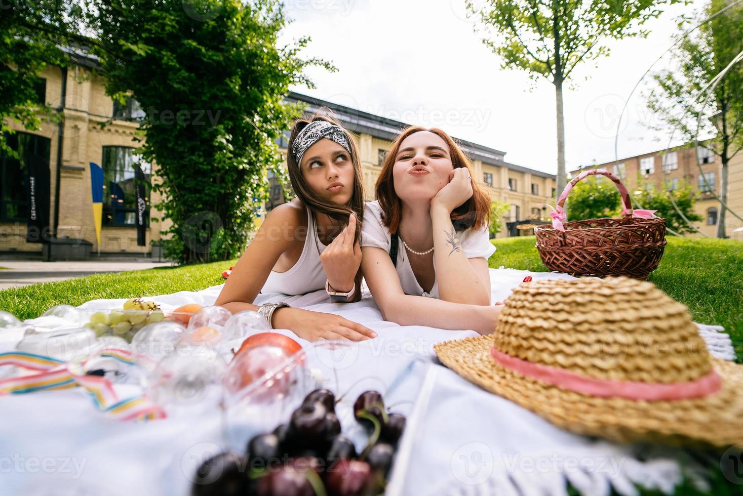 duas mulheres fazendo piquenique juntas, deitadas no gramado do parque foto