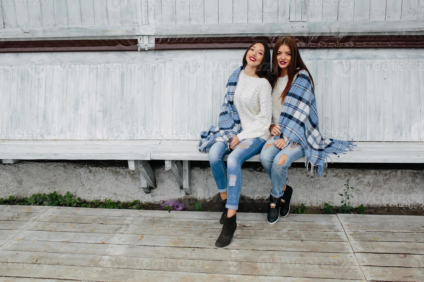 duas garotas sentam em um banco no parque foto