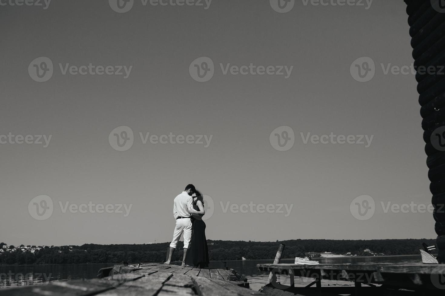 abraçando homem e mulher apaixonada no cais de madeira foto