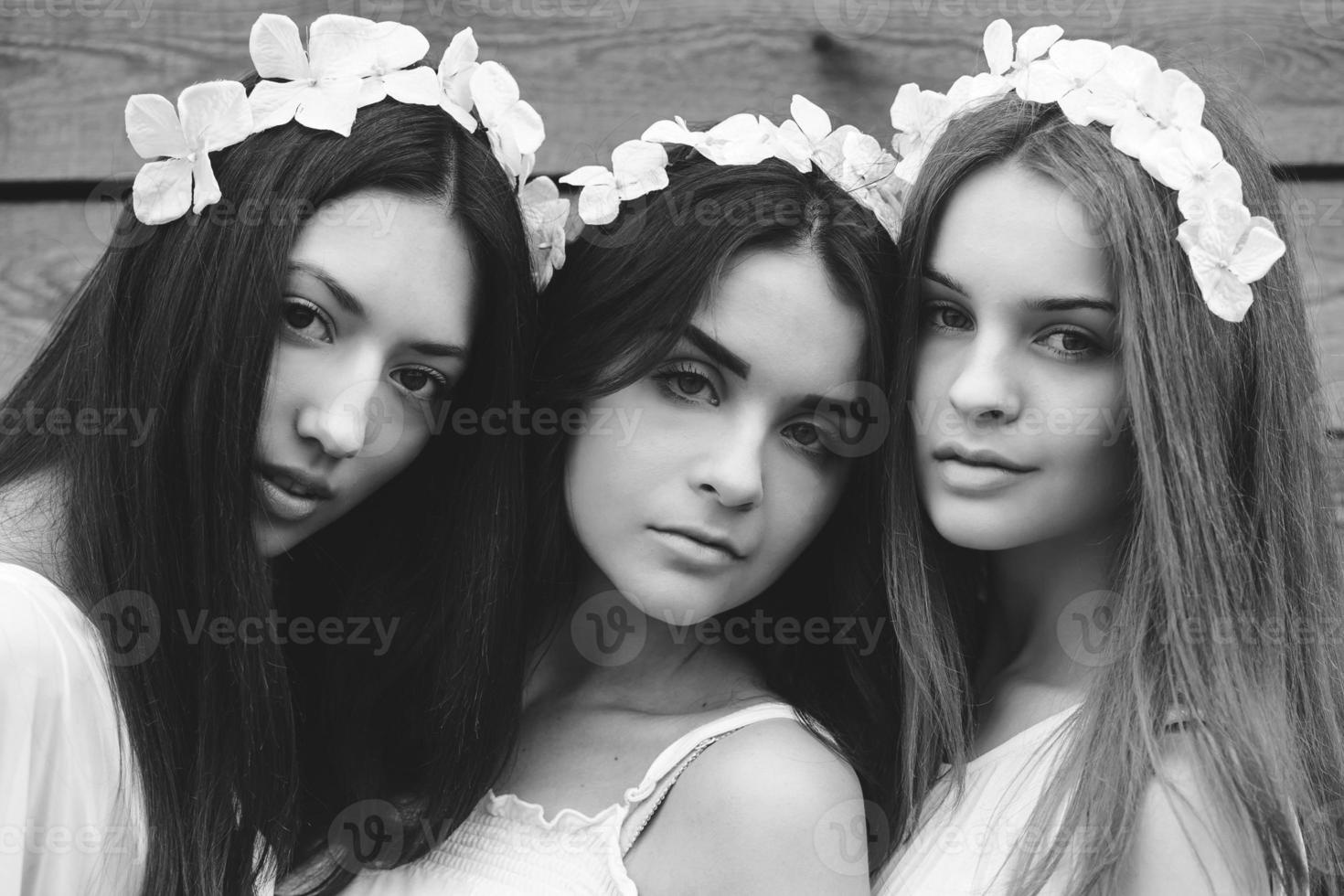 três garotas encantadoras perto de uma casa de madeira foto