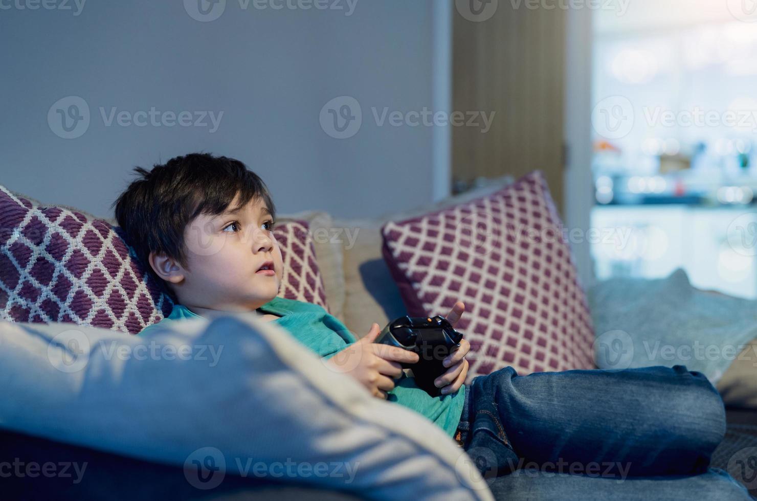 criança feliz segurando videogame ou console de jogos. criança se divertindo jogando online em casa enquanto a escola está fora, menino fica em casa durante o bloqueio covid, quarentena e distanciamento social ou auto-isolamento foto