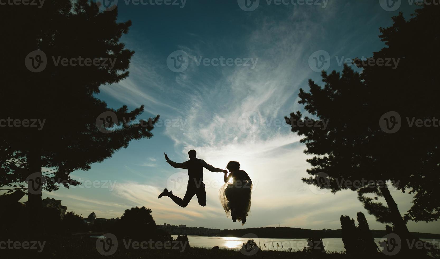 noivo e noiva pulando contra o lindo céu foto