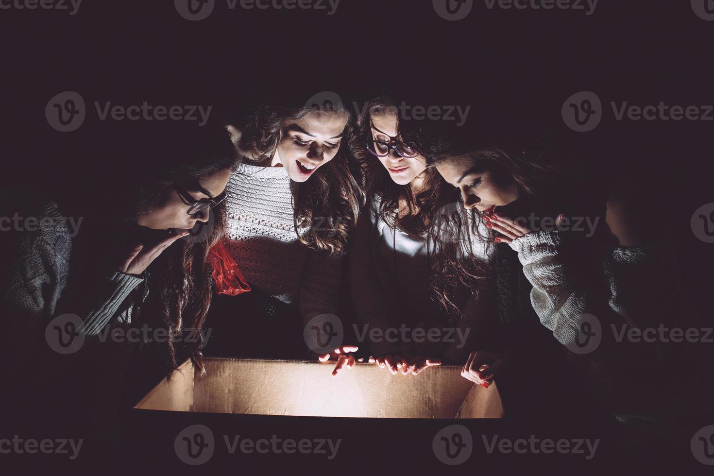 irmãs abre uma caixa com um presente de natal e um olhar fascinado dentro foto