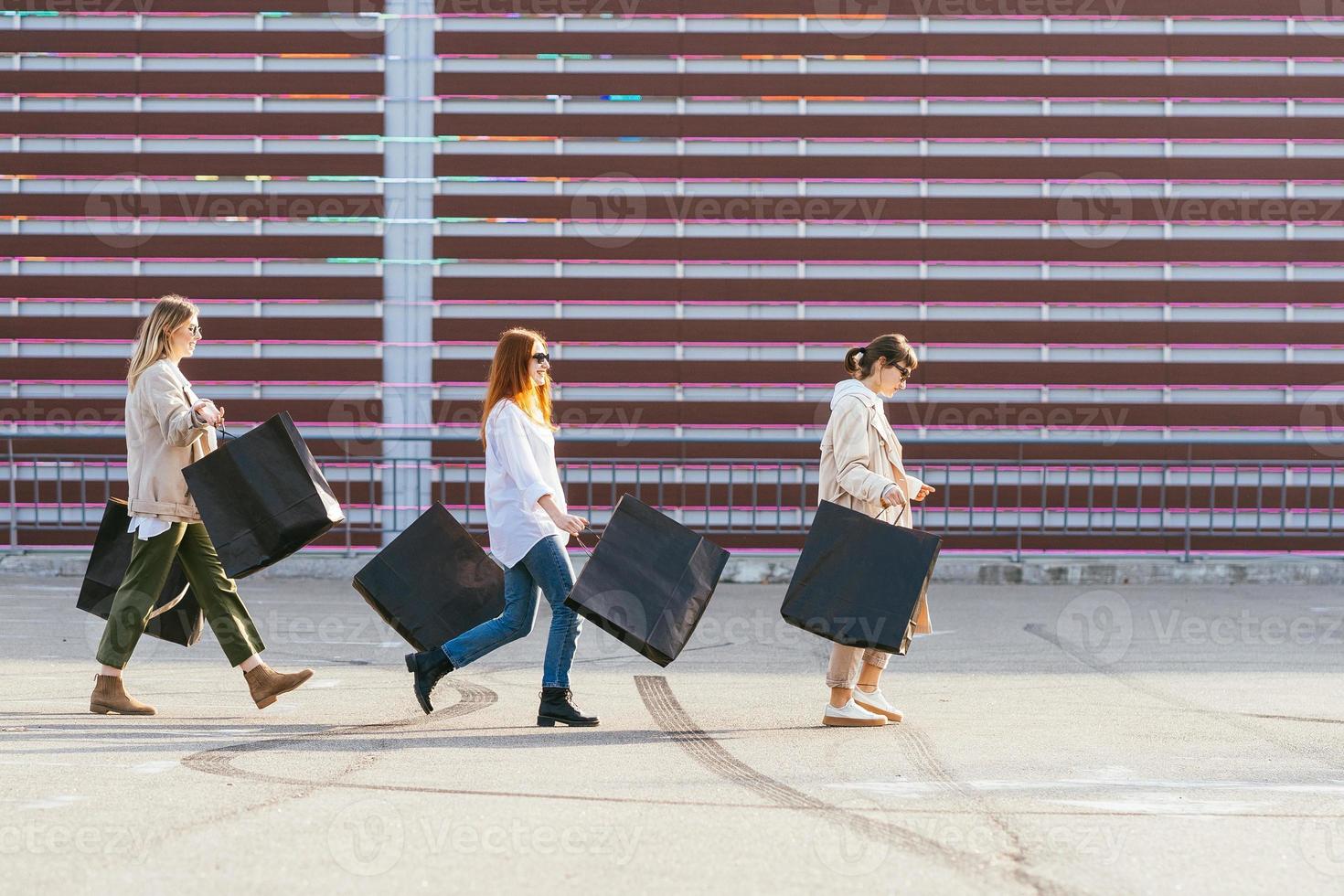 mulheres jovens com sacolas de compras andando na rua. foto