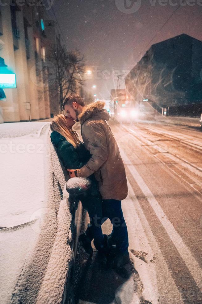 casal adulto jovem se beijando na rua coberta de neve foto