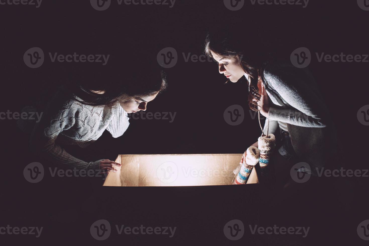 irmãs abre uma caixa com um presente de natal e um olhar fascinado dentro foto