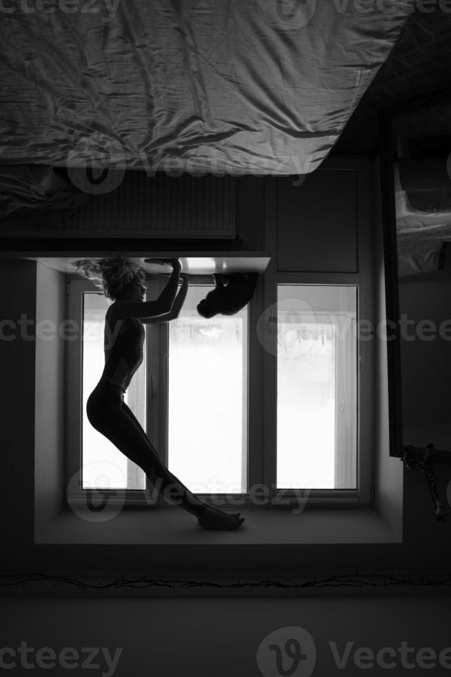 mulher fazendo yoga asana no peitoril da janela foto