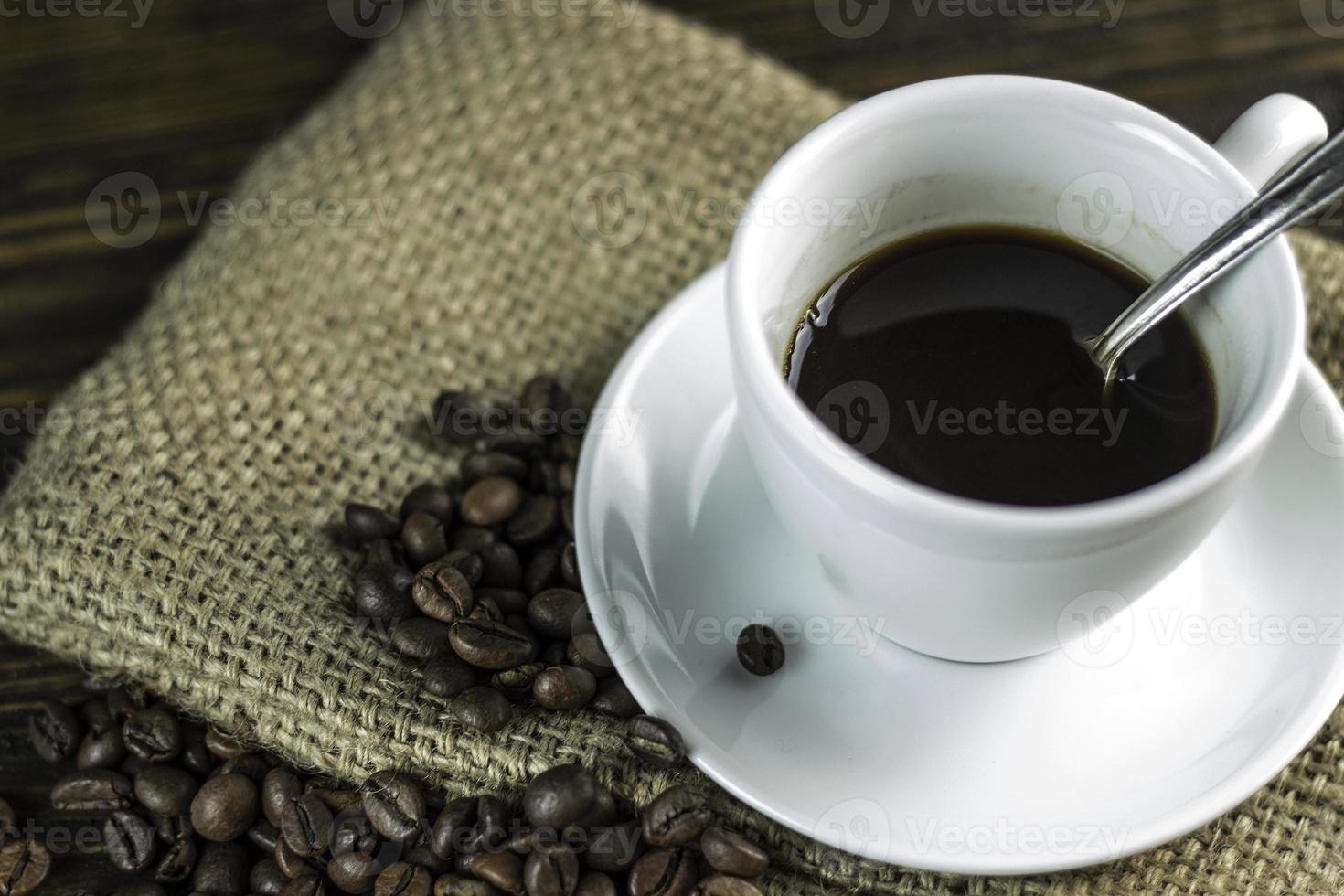 xícara de café e grãos de café em um fundo de madeira áspero. foto