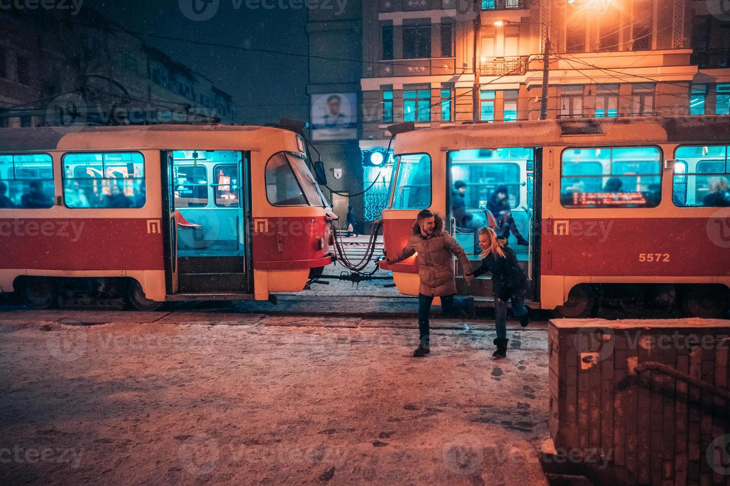 casal adulto jovem na estação de bonde coberto de neve foto