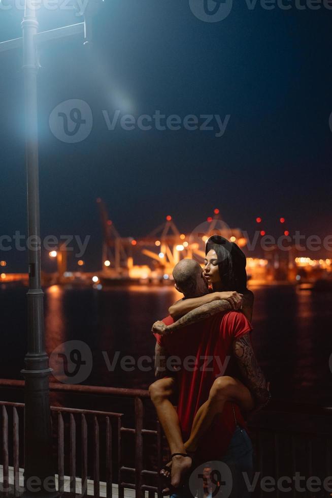 cara e garota se abraçando em um fundo do porto noturno foto