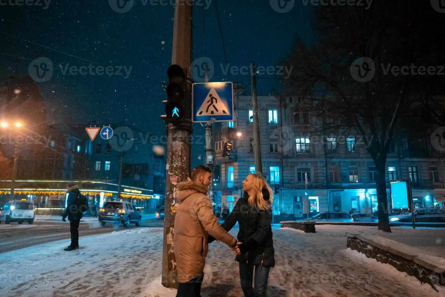 casal adulto jovem andando na calçada coberta de neve foto