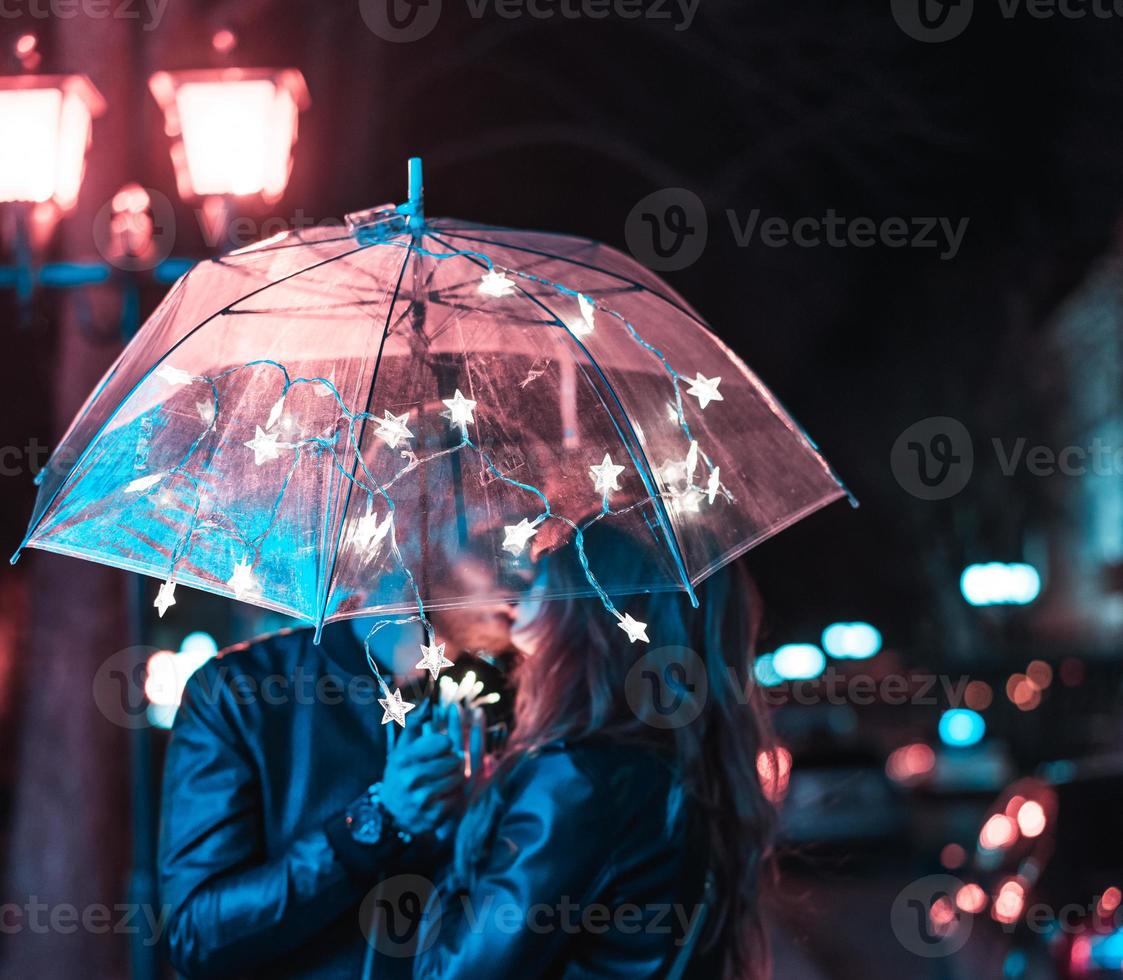 cara e menina se beijando sob um guarda-chuva foto