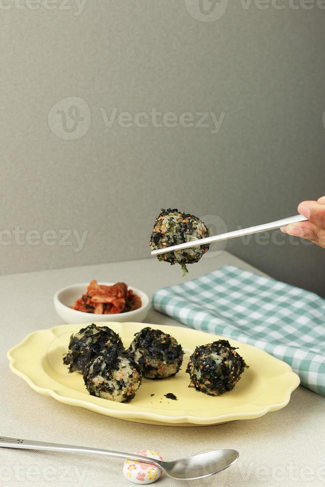 mão feminina segurando o palito, comer bola de arroz de algas coreanas jumeokbap foto