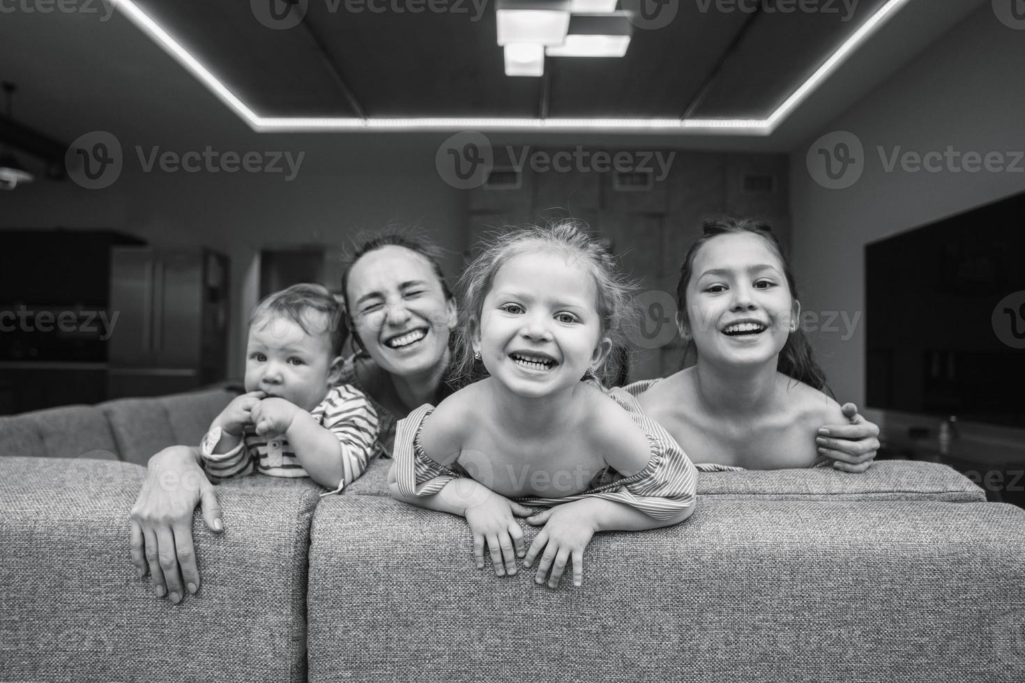 mãe, duas filhas e um filho pequeno no sofá foto