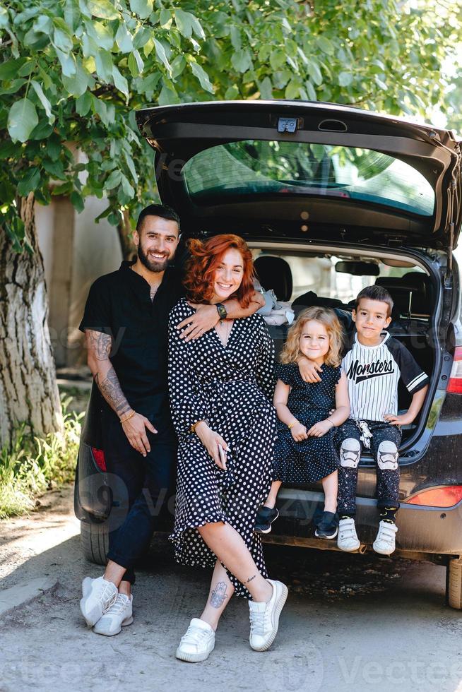 família feliz posando na câmera perto do carro foto