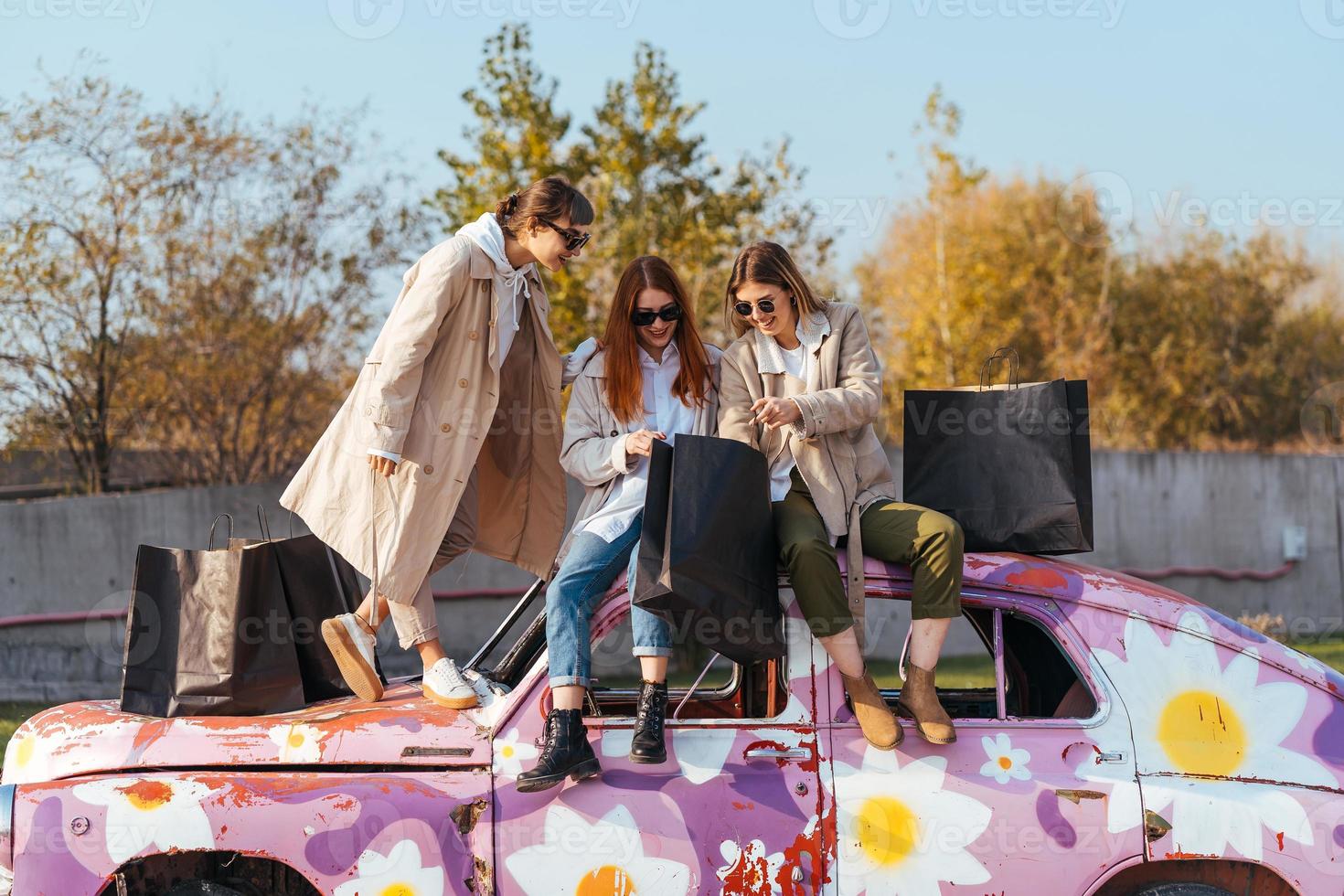 mulheres jovens posando no velho carro decorado foto