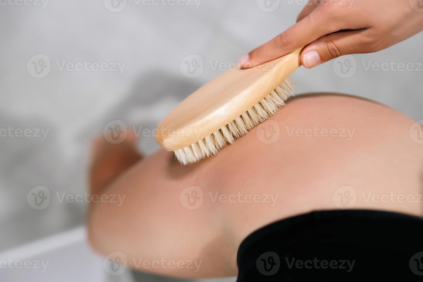 menina acariciando a perna com uma escova no banheiro foto