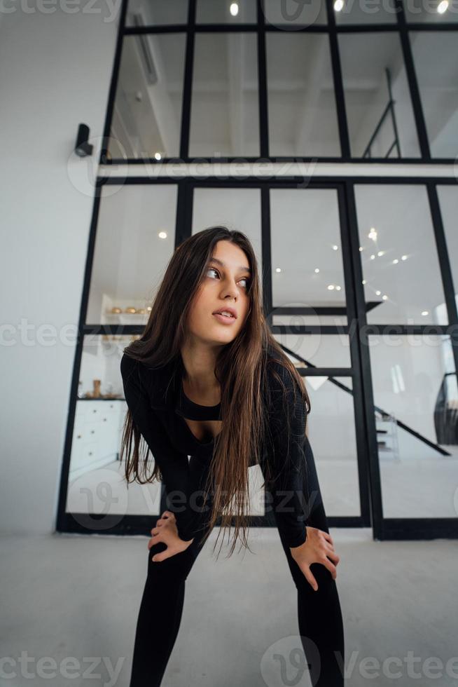 uma mulher em um agasalho preto se inclina para a frente e posa para a câmera foto