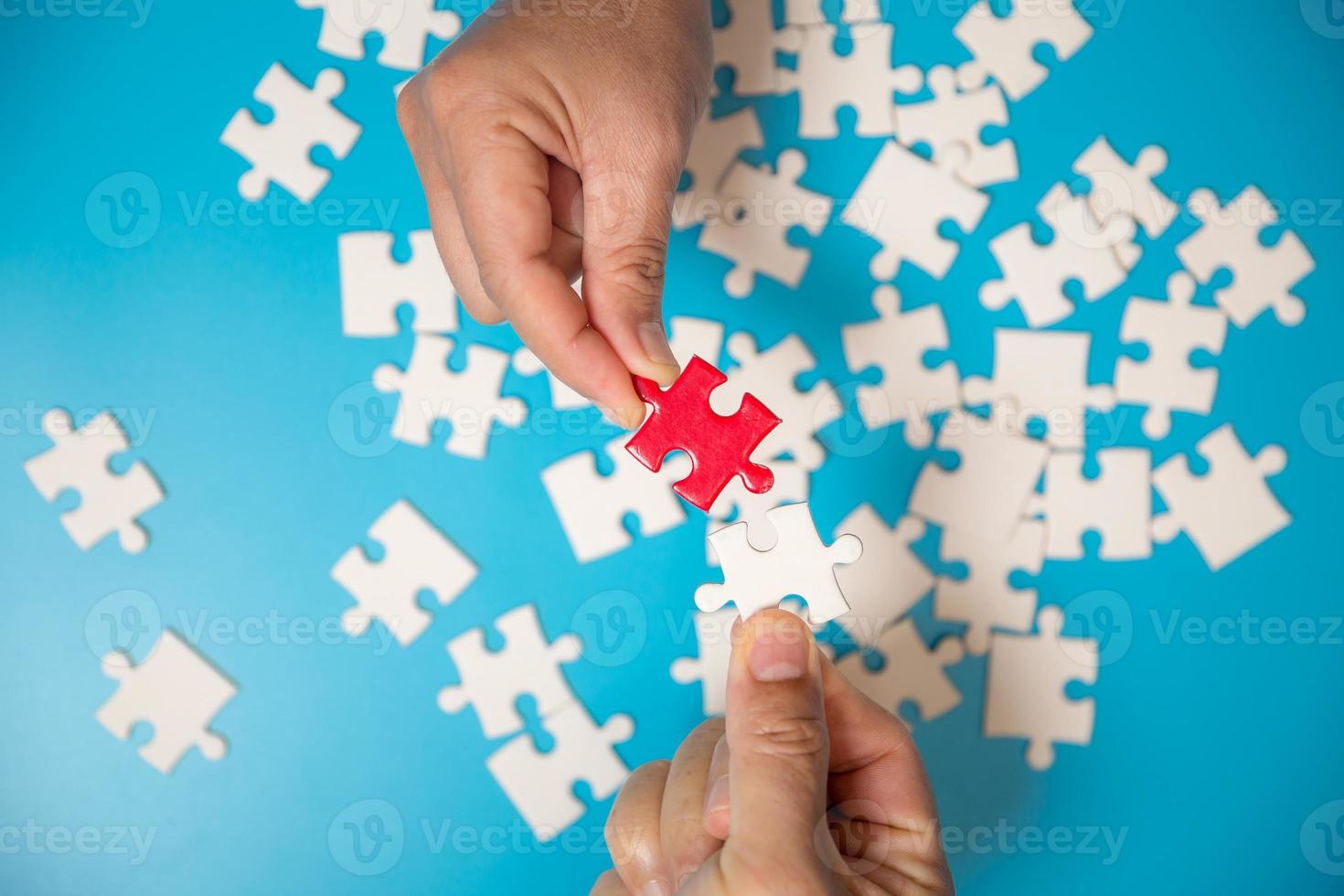 feche a mão segurando e jogando o jogo de quebra-cabeça incompleto. parte branca de peças de quebra-cabeça sobre fundo azul. conceitos de resolução de problemas, negócios, trabalho em equipe. foto