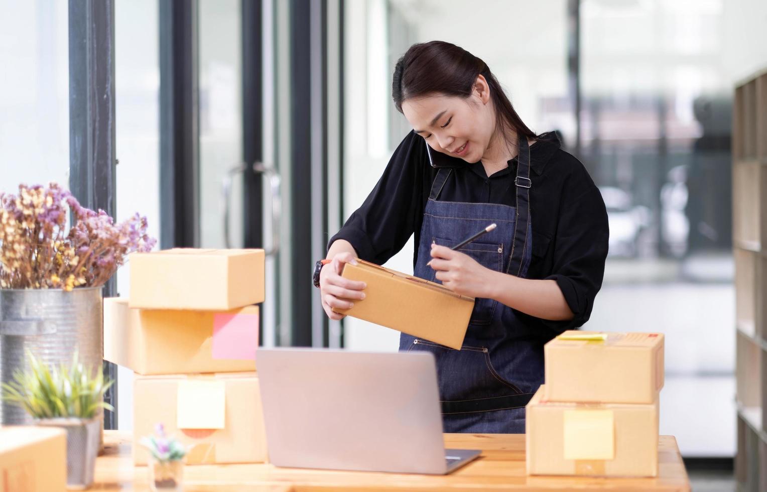 startup de pequenas empresas, proprietário do empresário usando smartphone e verificando o pedido de compra de compra on-line para preparar a caixa do produto do pacote. vendendo conceito de ideias online foto