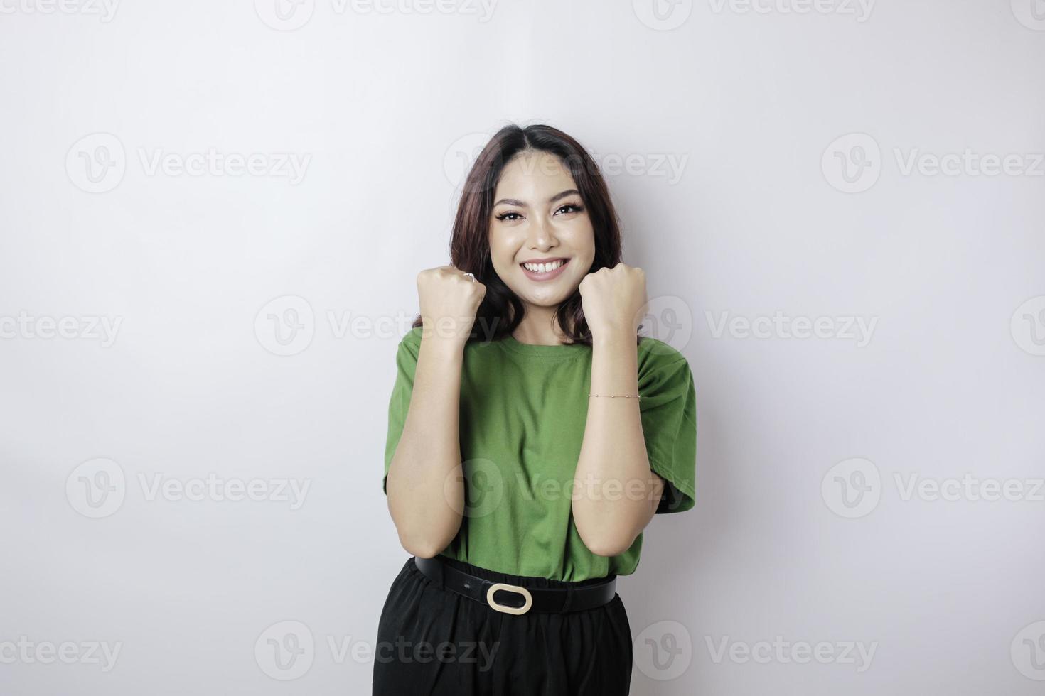 uma jovem mulher asiática com uma expressão de sucesso feliz vestindo camisa verde isolada por fundo branco foto