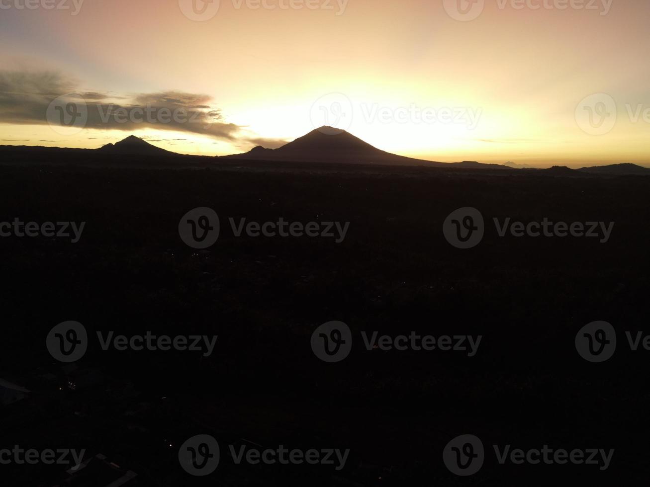 nascer do sol sobre a encosta com longos raios de sol passam pelo vale na vila de bali, indonésia foto