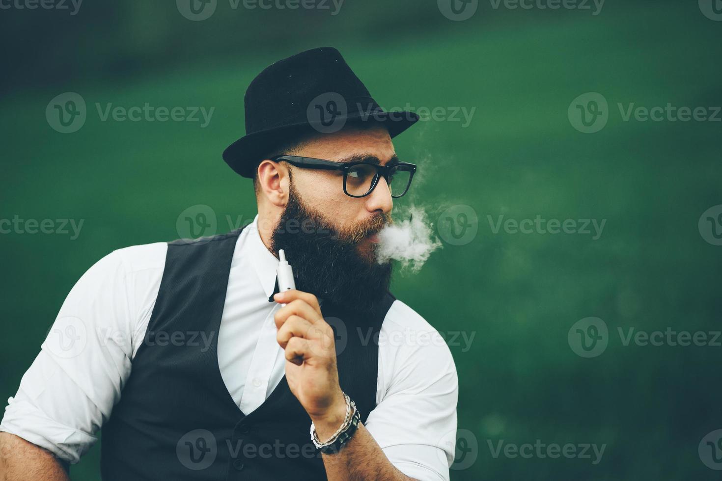 homem de barba fuma cigarro eletrônico foto