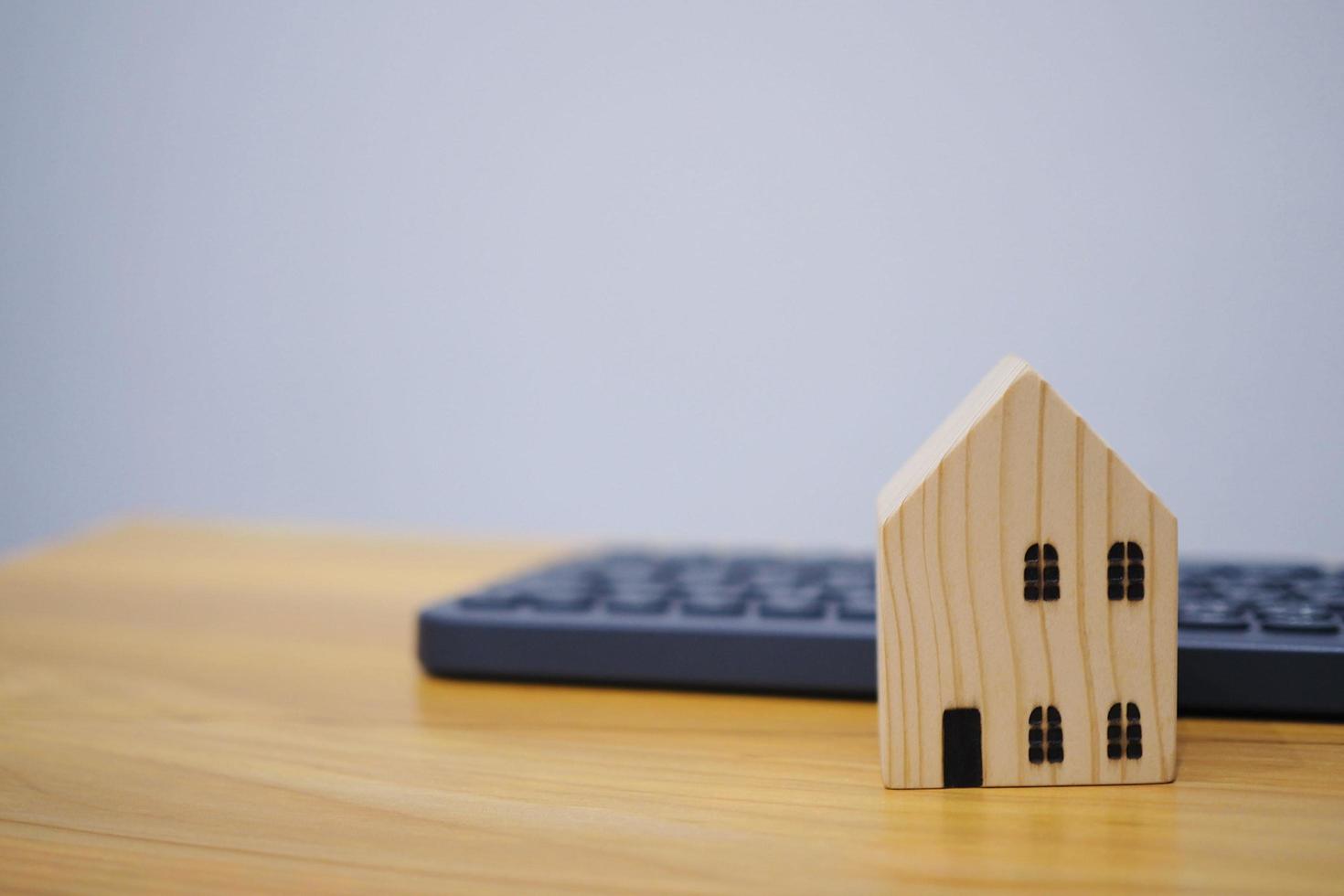 casa de madeira ao lado de ideias de negócios imobiliários de teclado, procurando alugar ou comprar uma casa foto