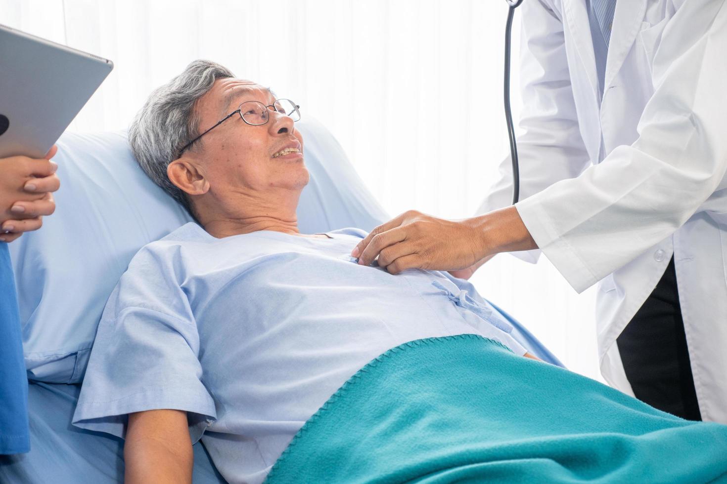 médico auscultando para homens pacientes asiáticos usando estetoscópio no quarto do hospital foto