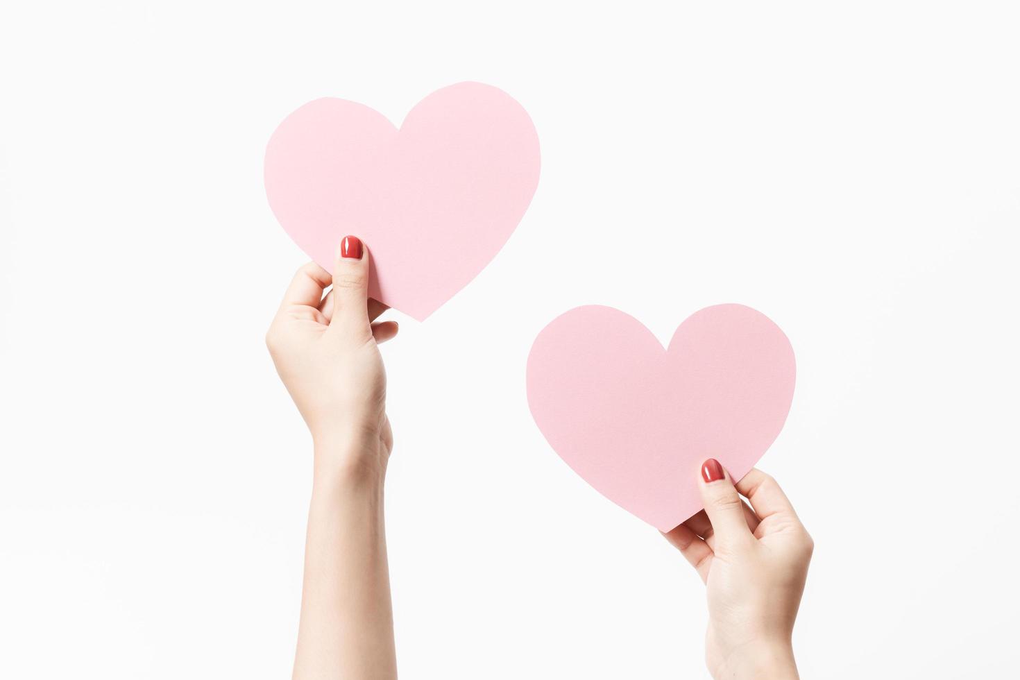 Feche as mulheres segurando papel em branco rosa com forma de coração em fundo branco. foto
