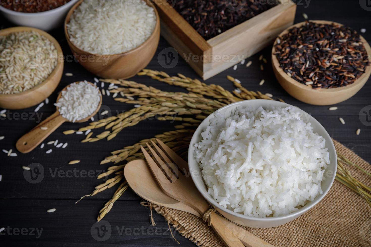 arroz cozido no vapor com arroz orgânico e sementes de arroz em casca na mesa de madeira foto