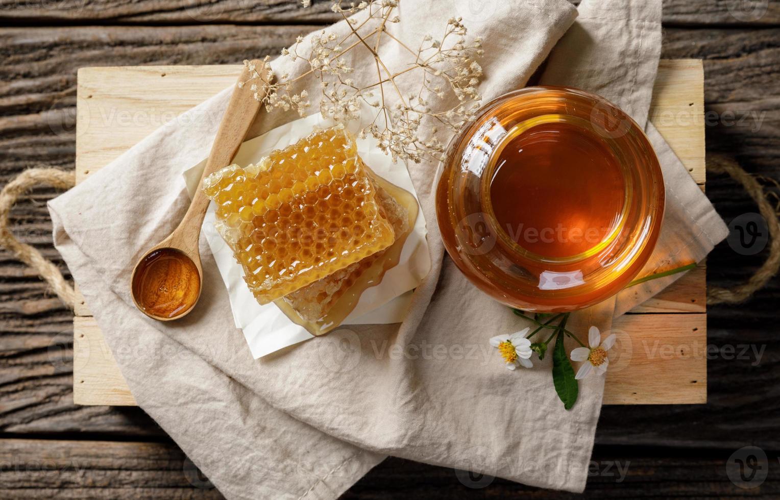abelha de mel em pote e favo de mel com concha de mel e flor na mesa de madeira, produtos apícolas pelo conceito de ingredientes naturais orgânicos foto