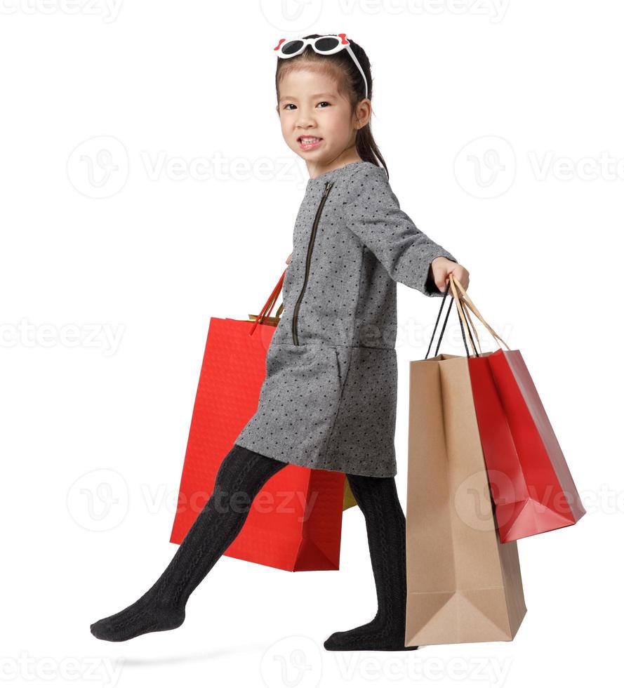 comprando uma jovem asiática segurando sacolas de compras e andando, isolado no fundo branco do estúdio com espaço de cópia, conceito de estilo de vida de marketing digital de comércio eletrônico foto