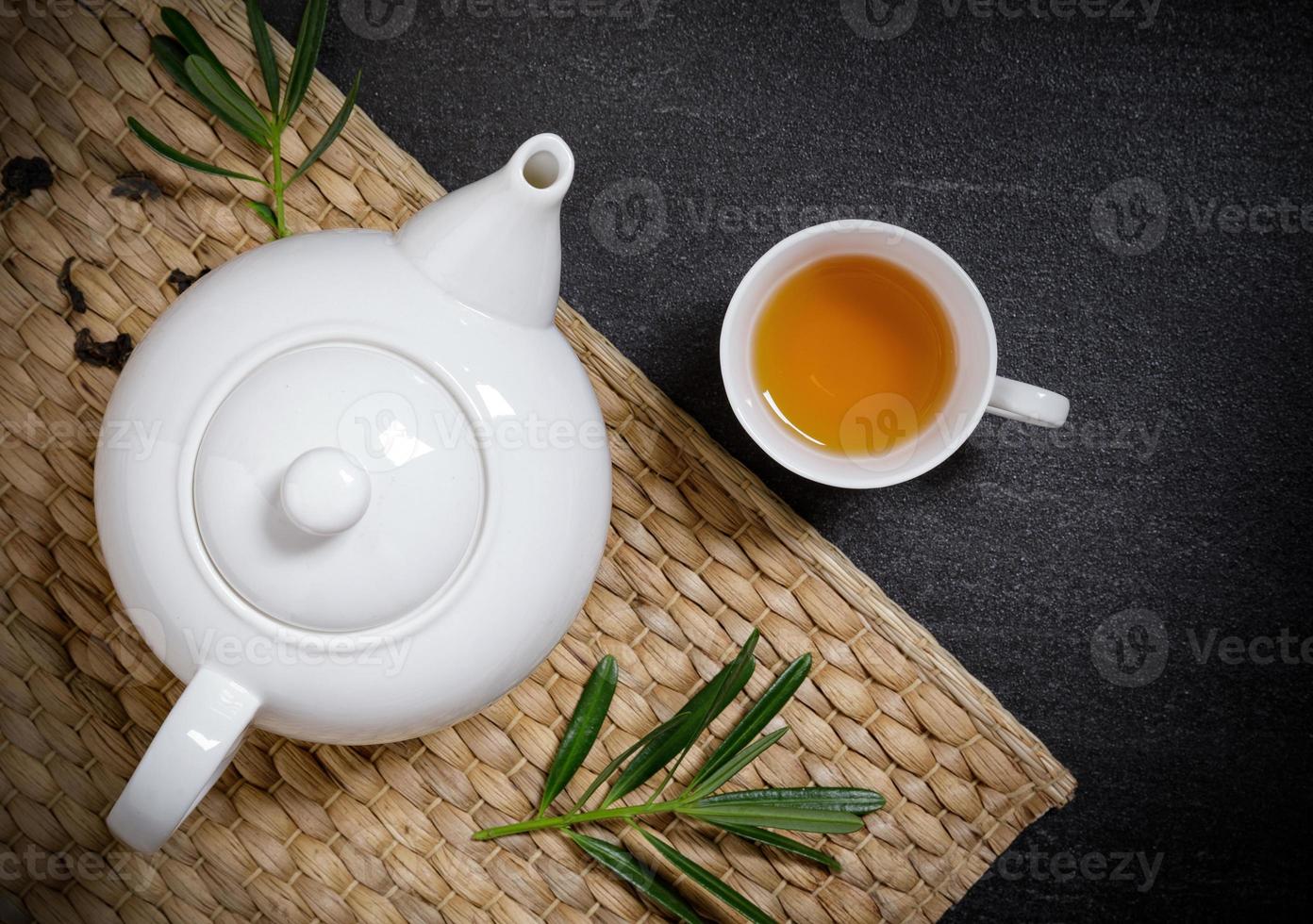 xícara de chá quente com jarros fumegantes e chá seco no tapete de prato no fundo da mesa de pedra preta com copyspace para o seu texto. foto