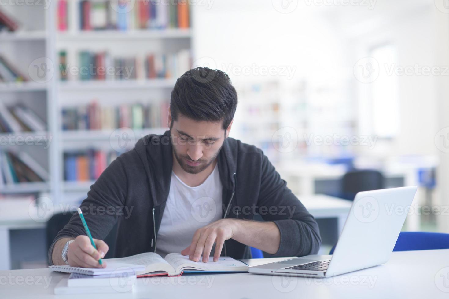 estudante na biblioteca da escola usando laptop para pesquisa foto