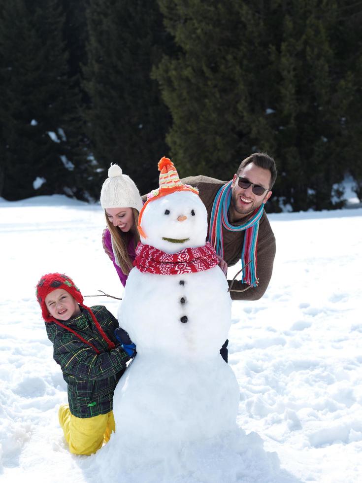 família feliz fazendo boneco de neve foto